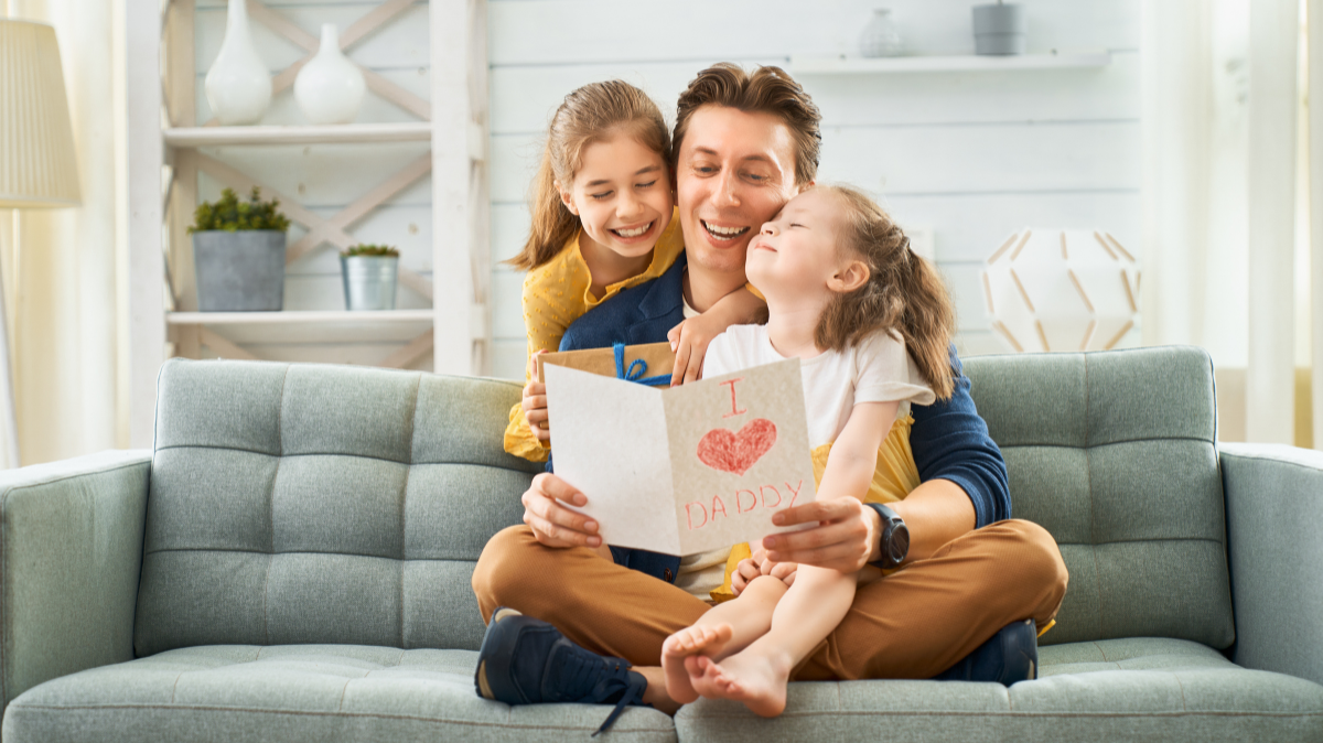 Father reading card with daughters