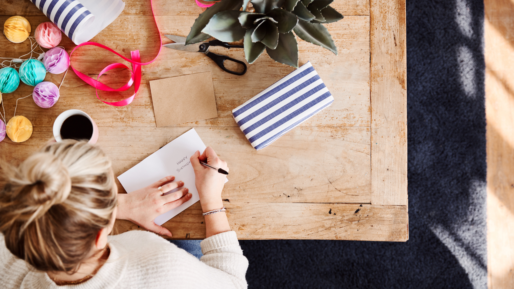 Woman writing Happy Birthday on a greeting card