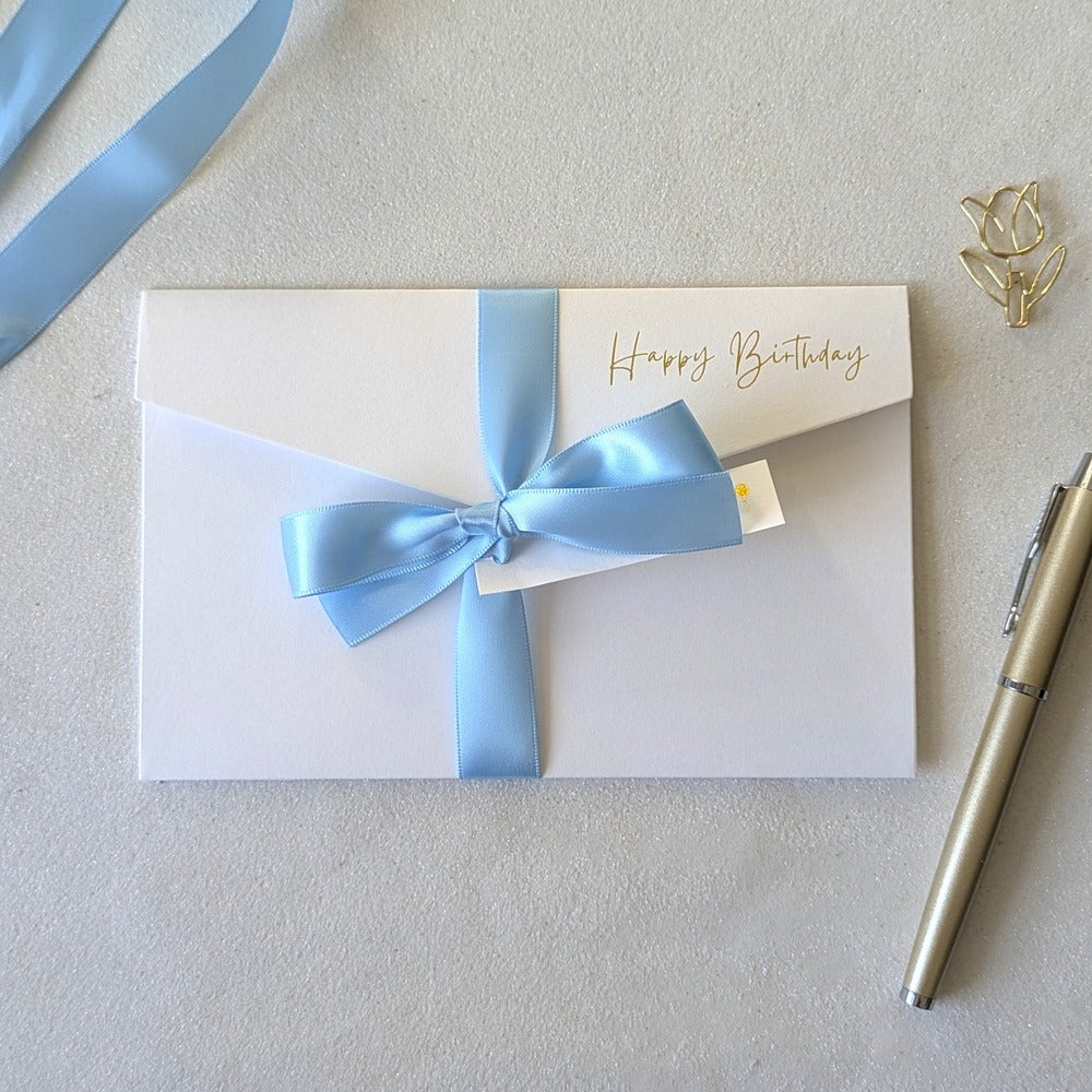 White birthday card with blue satin ribbon and pocket for the gift voucher