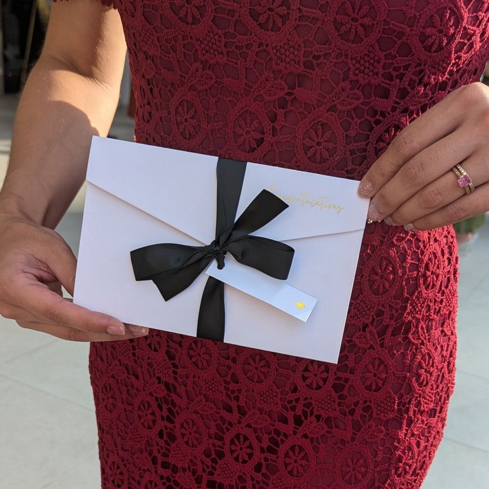 Woman in red dress holding white wedding greeting card for cash gift