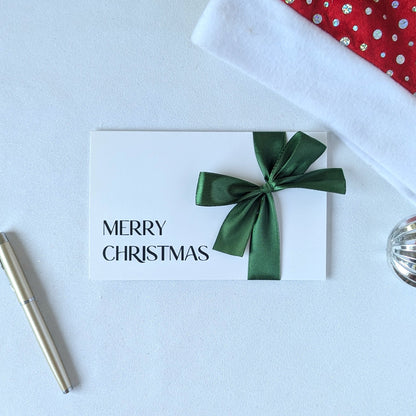 Christmas money wallet envelope for cash gift with money in the gift pocket. Green satin ribbon and black vinyl Merry Christmas