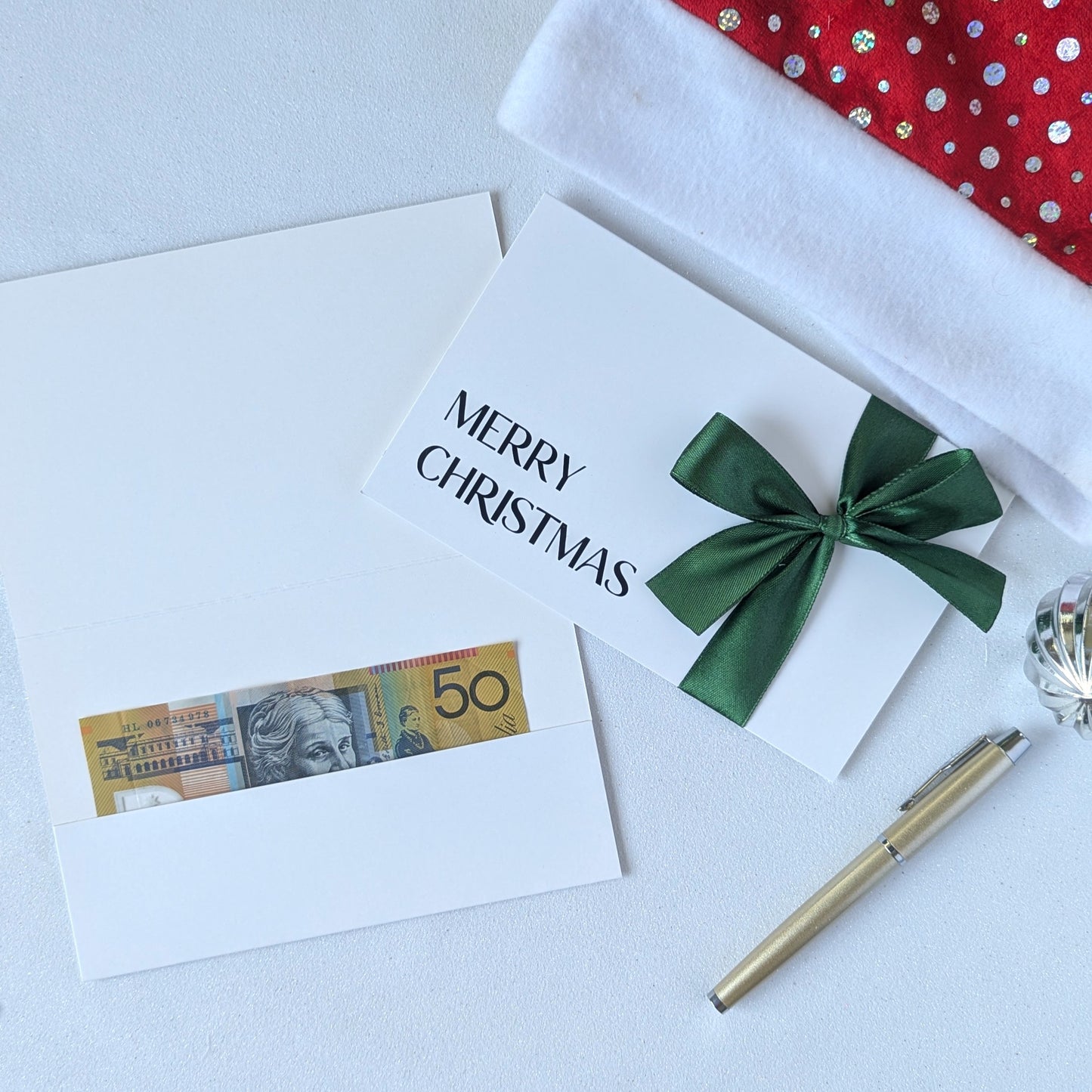 Christmas money wallet envelope for cash gift with money in the gift pocket. Green satin ribbon and black vinyl Merry Christmas