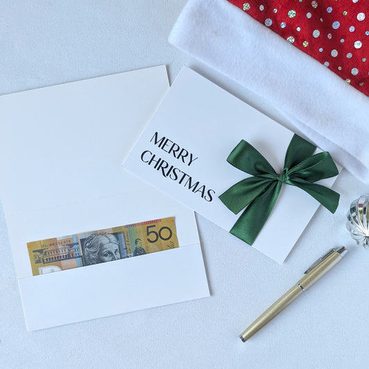 Christmas money wallet envelope for cash gift with money in the gift pocket. Green satin ribbon and black vinyl Merry Christmas