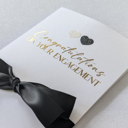 Close up of Congratulations on your engagement gift envelope with black and white glitter hearts and black satin ribbon
