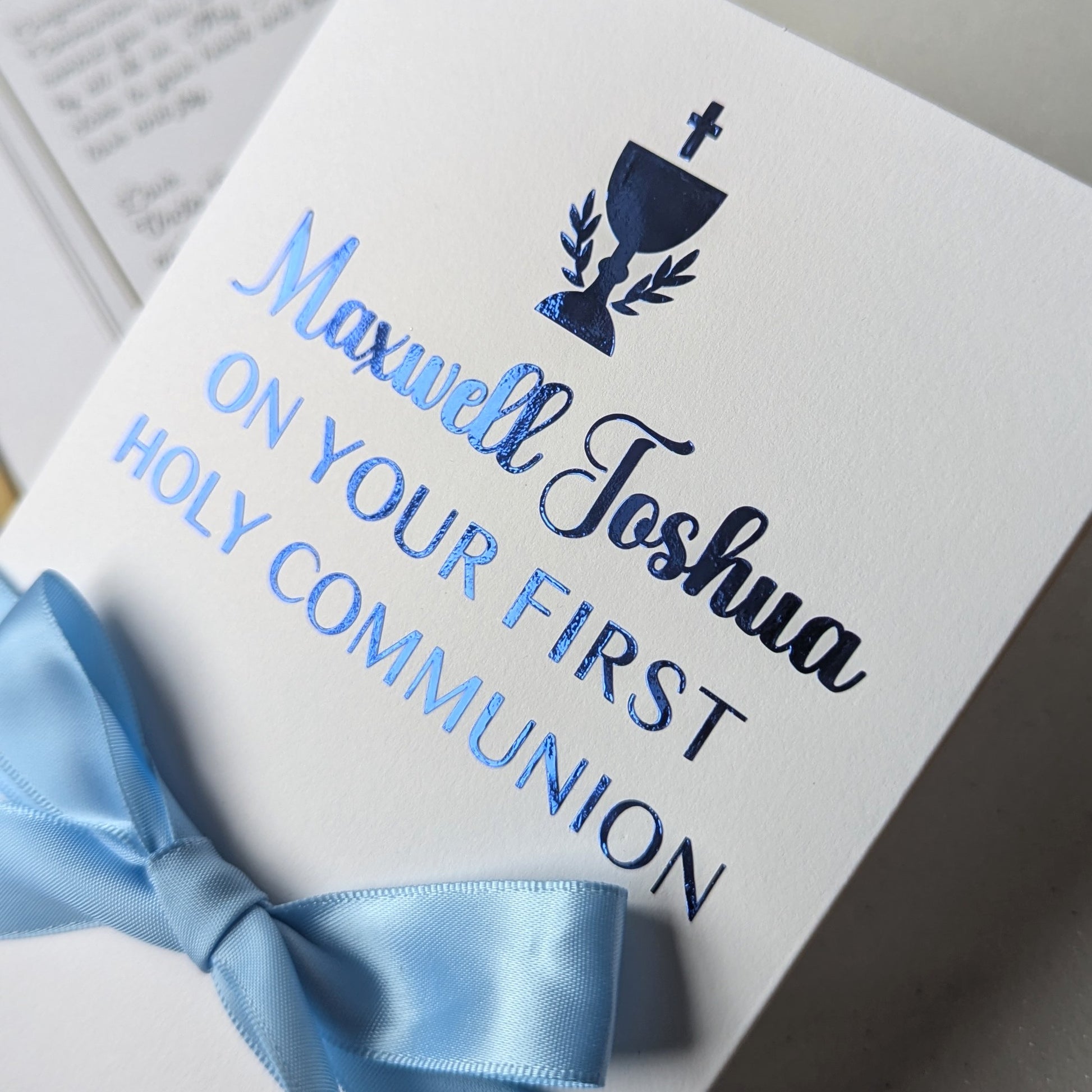 Close up of Personalised Holy communion money gift envelope greeting card with blue personlaised On your first holy communion with blue satin ribbon