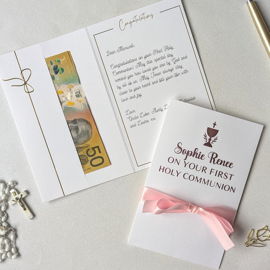 Holy communion money gift envelope greeting card with pink personlaised On your first holy communion with pink satin ribbon and pocket for the cash gift with message written inside the card