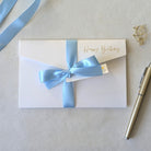 White birthday card with blue satin ribbon and pocket for the gift voucher