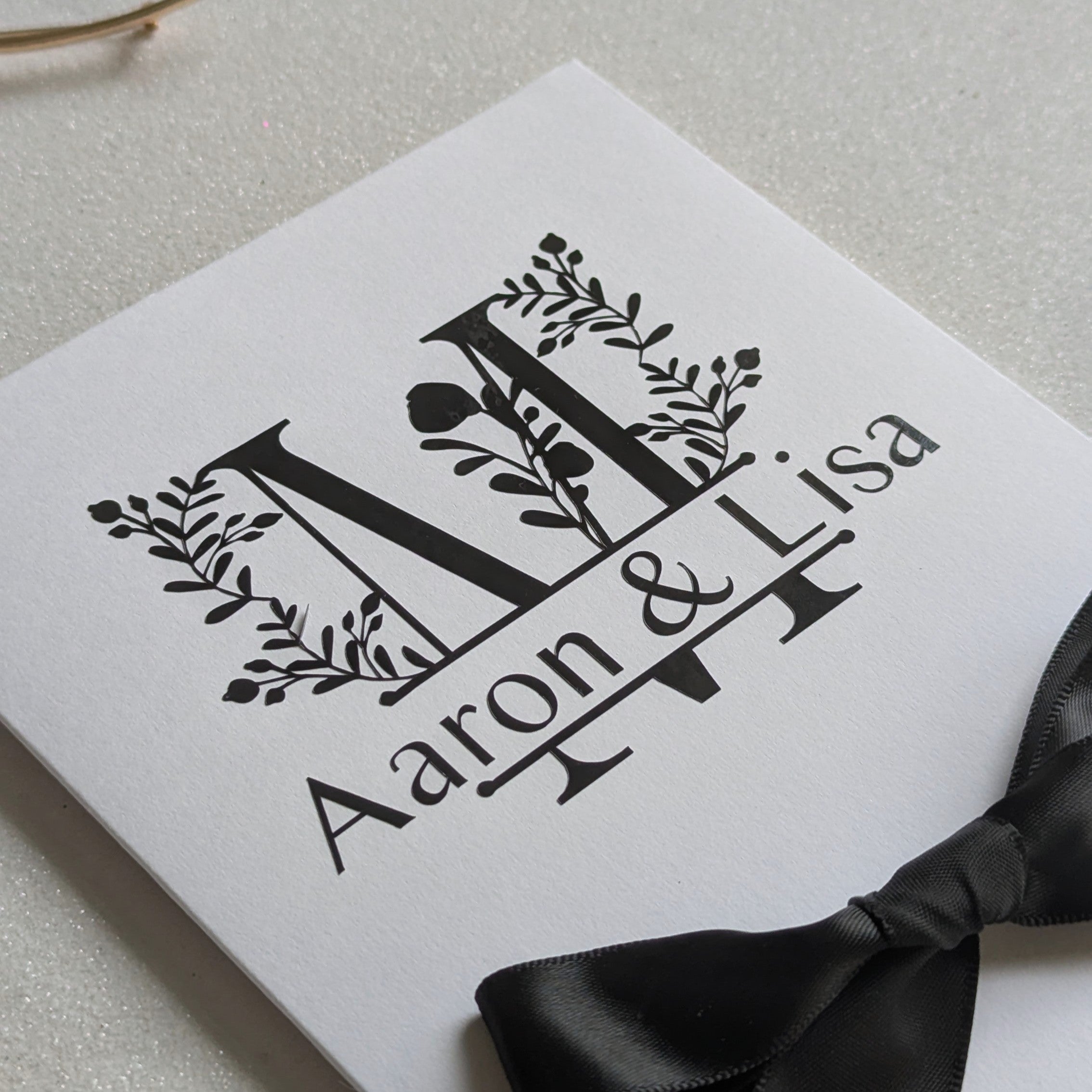 Monogram Personalised White wedding card with money pocket close up with Black vinyl monogram of Aaron and Lisa with a large floral M