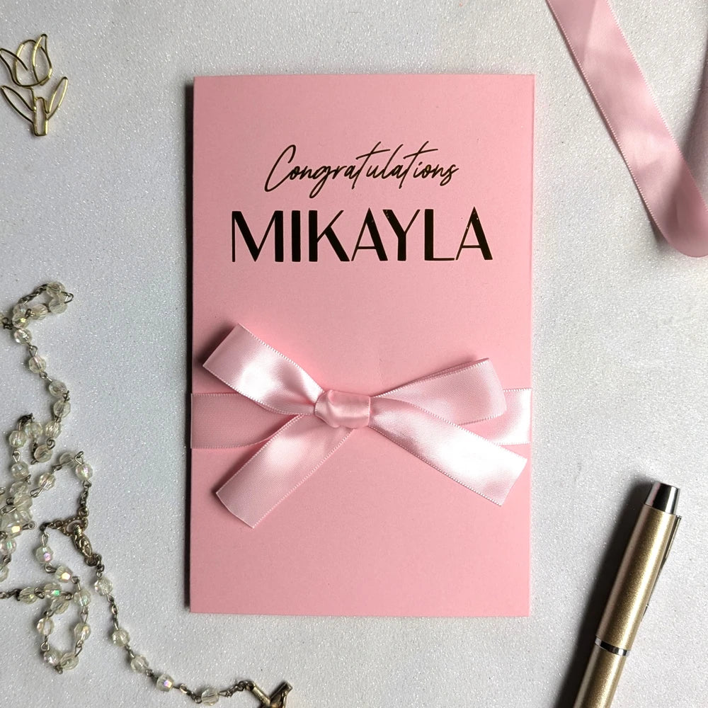 Pink bridal shower gift card holder for giving cash with custom "congratulations Mikalya" written on it in gold foil