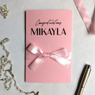 Pink bridal shower gift card holder for giving cash with custom "congratulations Mikalya" written on it in gold foil