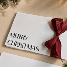 Elegant Merry Christmas Card printed in crisp black ink with a tied red satin ribbon