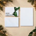 Merry Christmas card in crisp black ink white textured paper and green satin ribbon